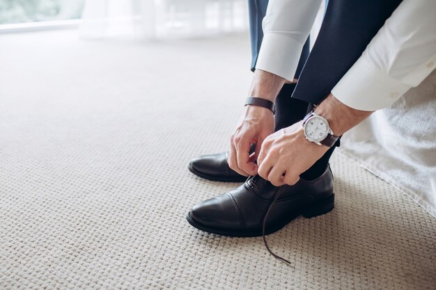 L'uomo sul lato del letto che mette le scarpe