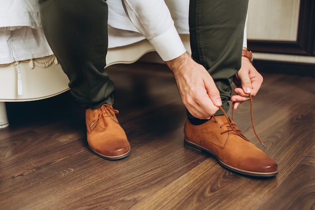 L'uomo sul lato del letto che mette le scarpe