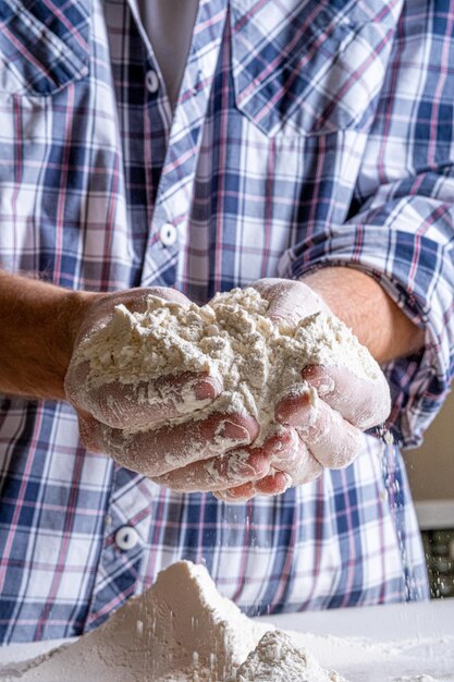 A man sifts flour through a sieve to make fresh bread Wheat flour of the highest grade for bread Flour aeration