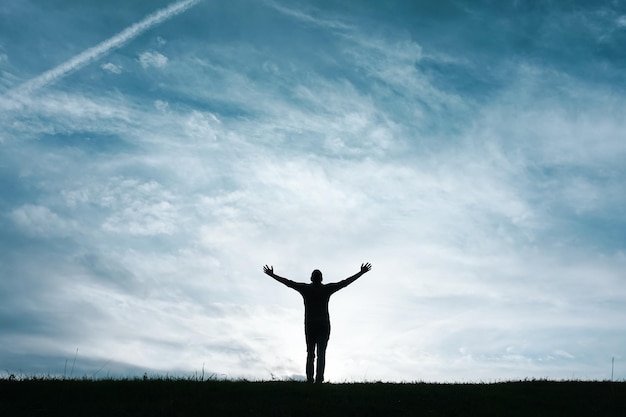 man silhouette feeling free among clouds in the mountain