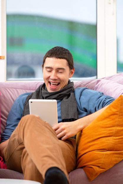 L'uomo si siede sul divano e utilizza un computer tablet