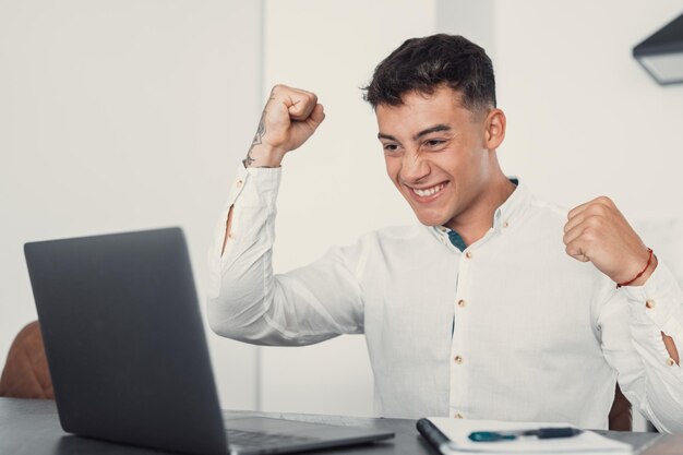 Man sit at desk read email on laptop makes yes gesture feels happy