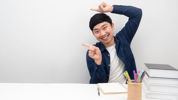 Man sit at the desk smiling gesture point finger at copy space