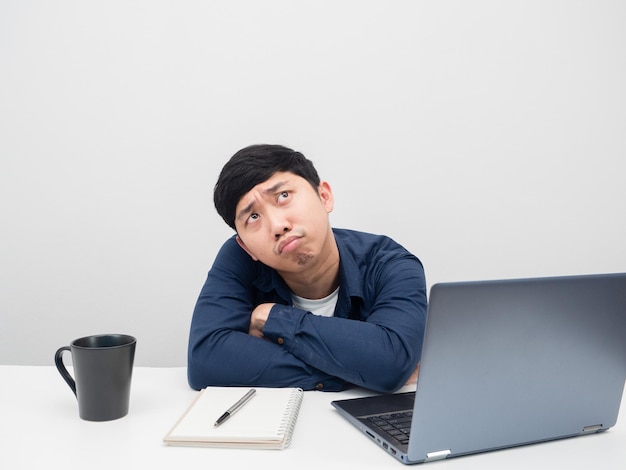 Man sit at the desk with workolace feeling bored and looking up