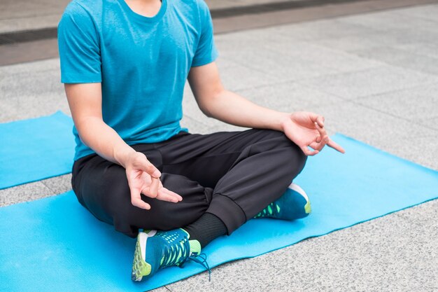 L'uomo si siede meditando con la mano di loto sul tappetino da yoga