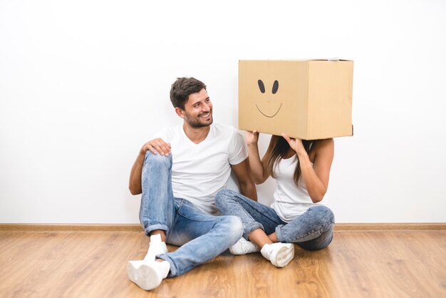 The man sit near woman with a carton box on the head