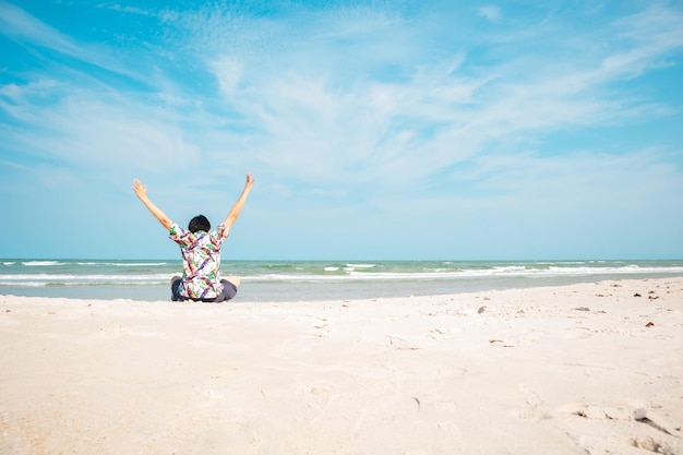 Photo man sits on the beach during the summer time enjoying the view