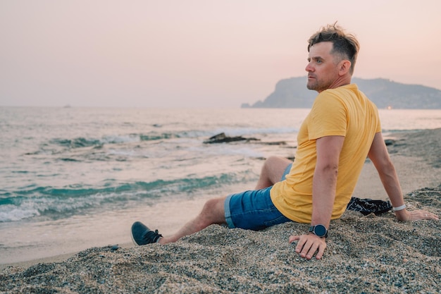 Man sits on the beach and looks at the sea in alanya city turkey travelling or vacation concept