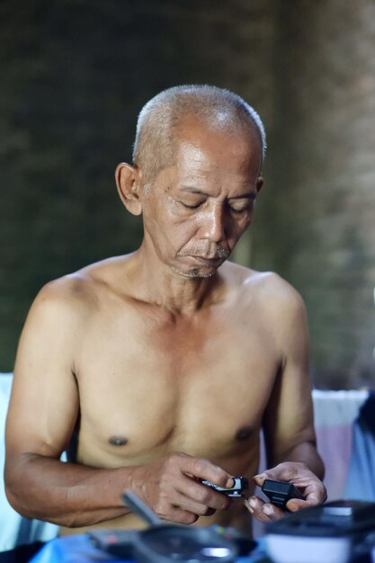 A man sits on a bed with his hands on his chest.