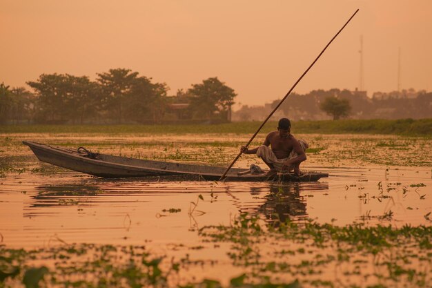 Photo a man sits in a boat in the flooded waters of the lake.