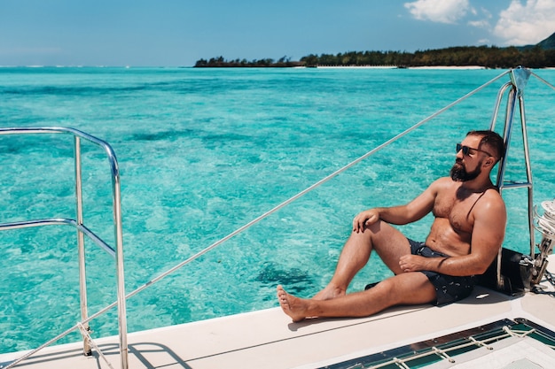 Un uomo si siede su un catamarano nell'oceano indiano vicino all'isola tropicale di mauritius.coral reef.