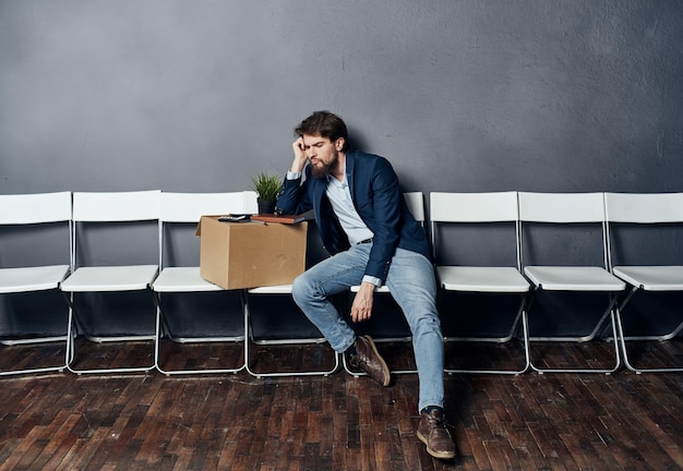 L'uomo si siede su una sedia scatola con cose che respingono la depressione del malcontento