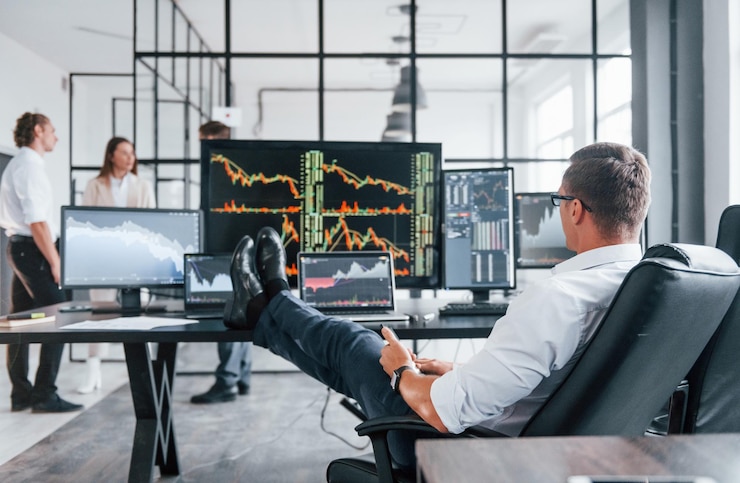 Photo man sits on chair and takes break team of stockbrokers works in modern office with many display screens