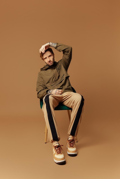 A man sits in a chair with a brown background and a green jacket with the word nike on it.