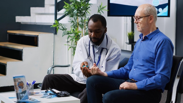 Photo a man sits in a chair with a stethoscope on his wrist, next to a man with a stethoscope on his neck.