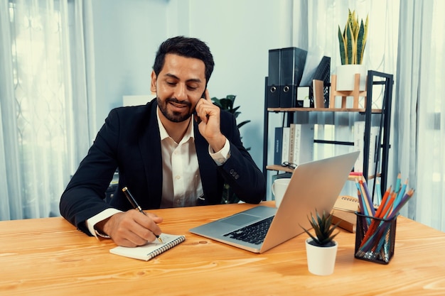 Photo a man sits at a desk in an office, writing on a notebook.