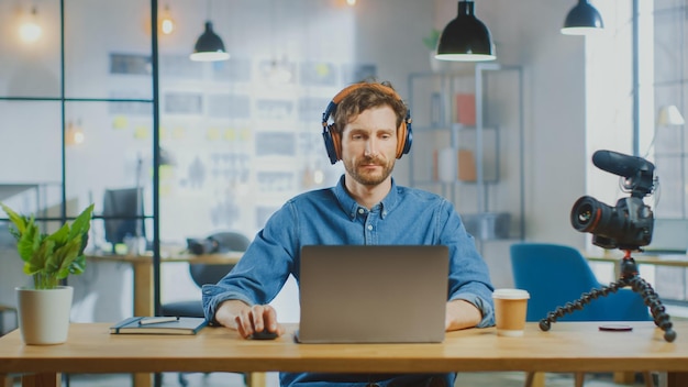 A man sits at a desk with a laptop and a cup of coffee on the table.