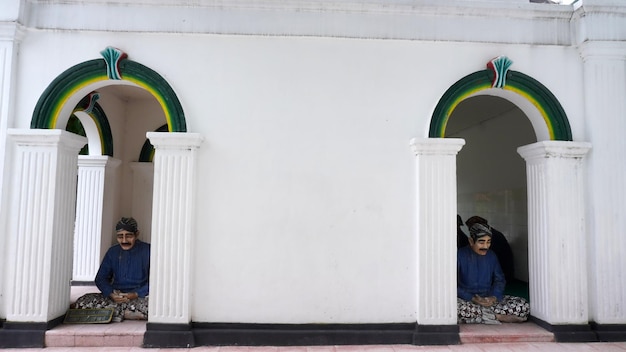 두 개의 기둥과 '거룩한 달'이라는 표지판이 있는 출입구에 남자가 앉아 있다.