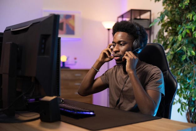 Man sits in front of computer puts on headphones tweaks microphone from kit looks into monitor