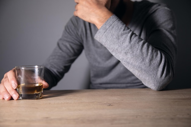 A man sits holding an alcoholic drink in his hand