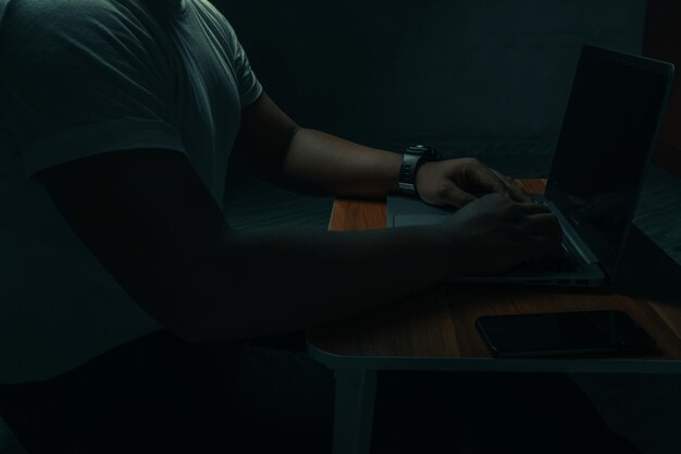 Photo a man sits on a laptop in a dark room concept is addicted to the internet