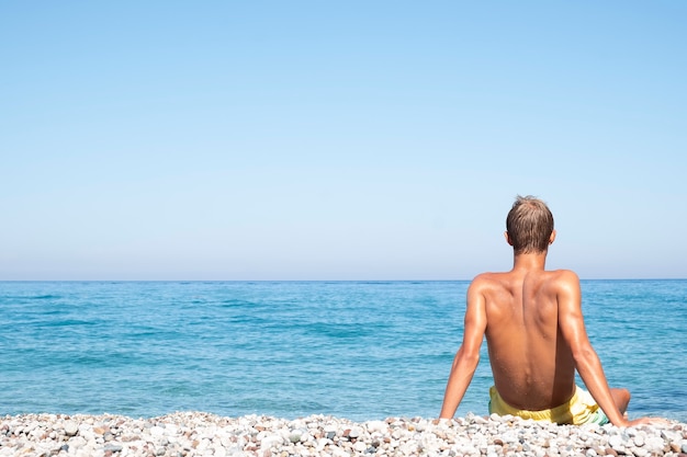 The man sits on the seashore. Summer vacation concept. Copy space