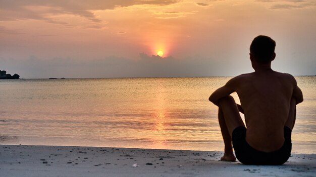 Man sits at sunrise on Koh Pangan in Thailand