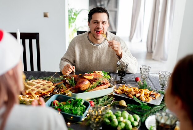 男はクリスマスディナーでテーブルに座っています