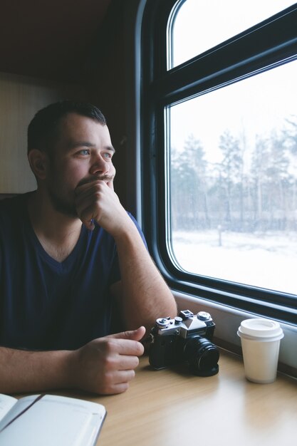 男はカメラで電車の中でテーブルに座っています