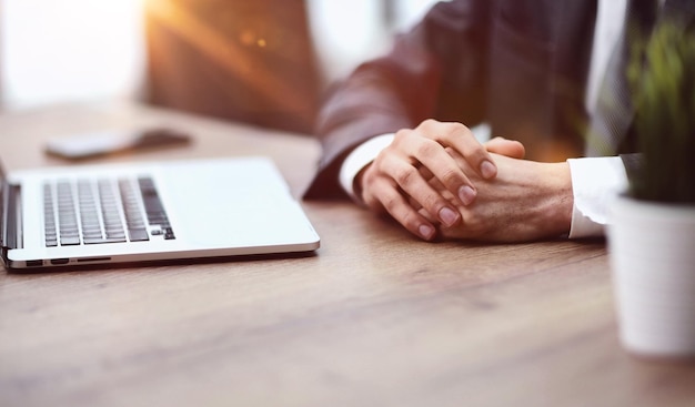 a man sits at a table with his hands clasped together