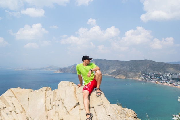 a man sits on top of a mountain and looks at the sea