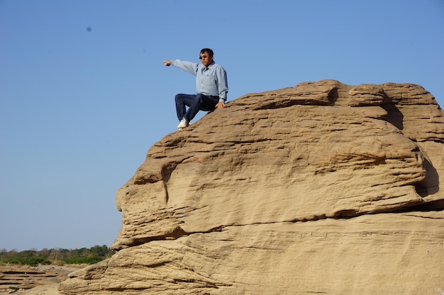 사진 은 하늘을 배경으로 바위 위에 앉아 있는 남자