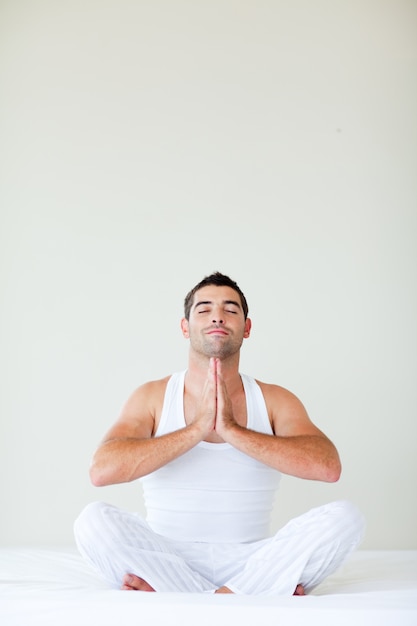 Man sitting on bed doing yoga with copy-space