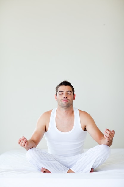 Man sitting on bed meditating