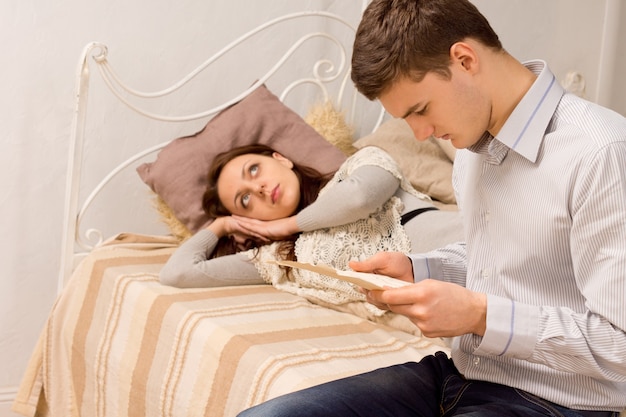 Man sitting on a bed reading a document