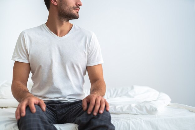 L'uomo seduto sul letto su sfondo bianco