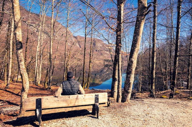 A man sitting on the bench and looking at the mountain lake