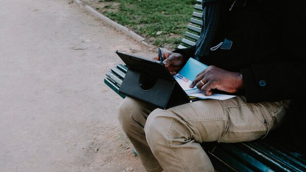 Photo man sitting on a bench and using a tablet stock photo