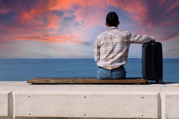 man sitting on bench with suitcase Sad man feeling lonely sitting on beach