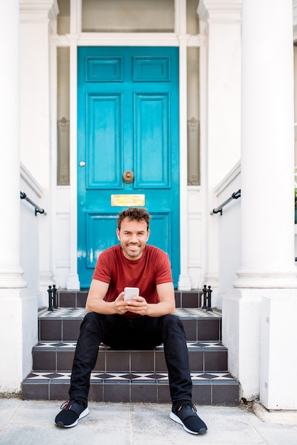 Man sitting in a blue door with mobile phone