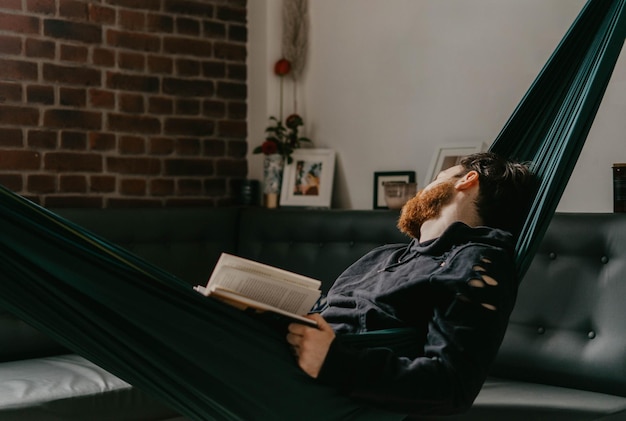 Человек сидит на книге у стены дома