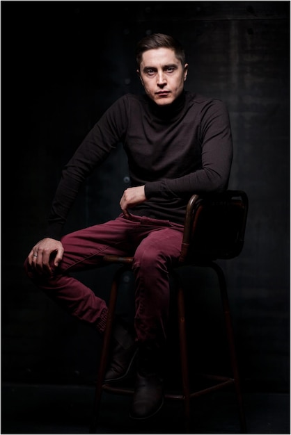 A man sitting on a brown leather chair on a black background.\
card emotions. man emotions