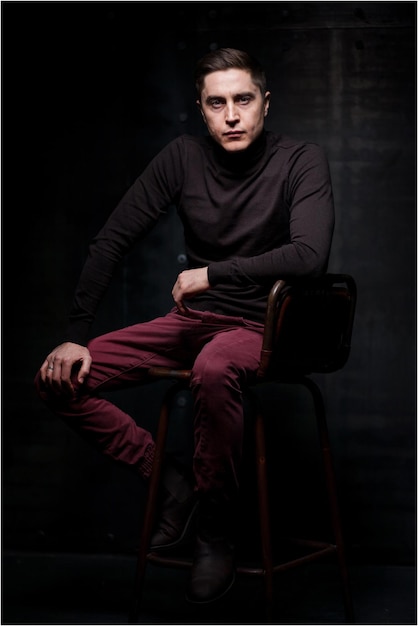 A man sitting on a brown leather chair on a black background. Card emotions. man emotions