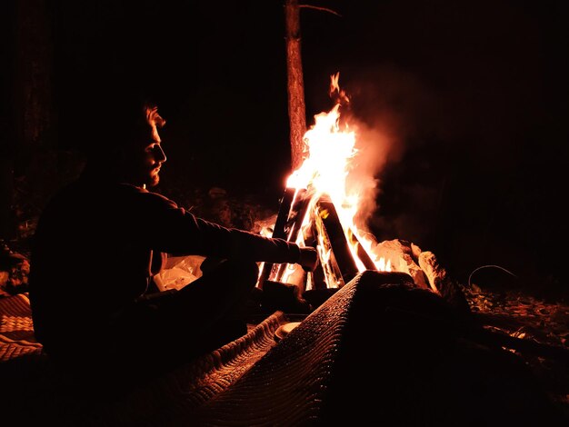 Photo man sitting by fire at night