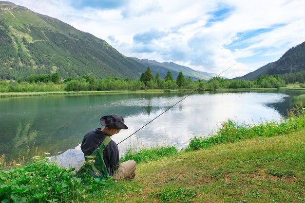 Man sitting by lake against mountains