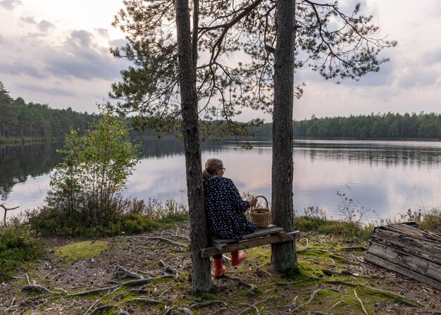 Man sitting by lake against sky