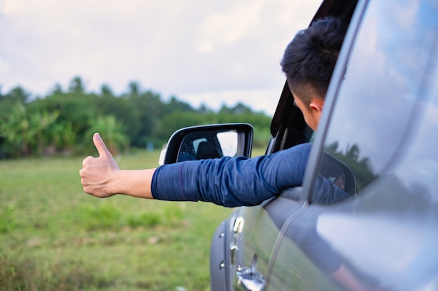 Man sitting in car happily reach out hand with thumb up.