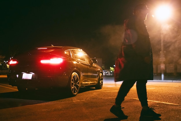 Photo man sitting next to car at night