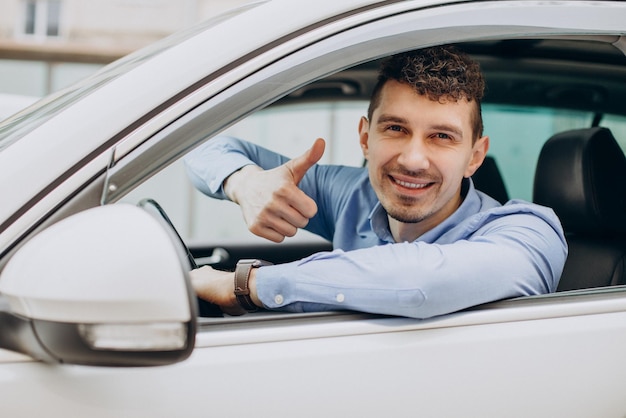 車に座って、窓越しに親指を見せている男