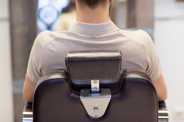 Photo man sitting in chair at barbershop or hair salon